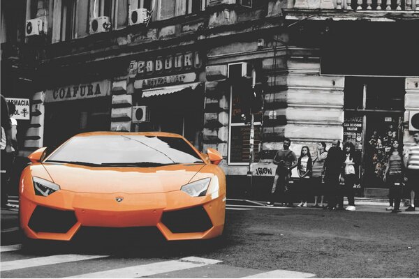 A colored car standing on the street of a black and white city