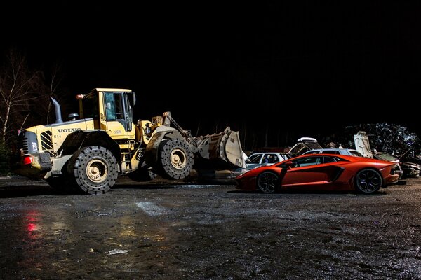 Volvo bulldozer at night with orange lamborghini