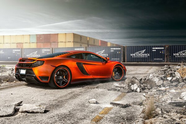 Orange McLaren MP4 vorsteiner on the background of containers