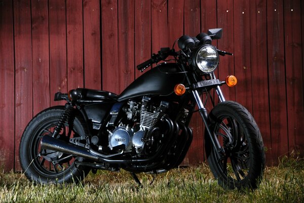 Motocicleta xj 650 en la hierba contra el fondo de una cerca de madera