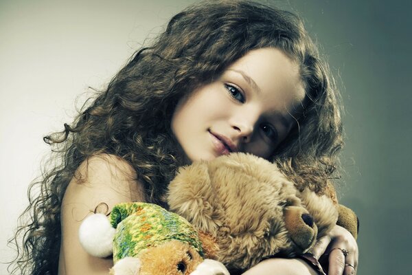 A beautiful girl holds soft teddy bears in her hands