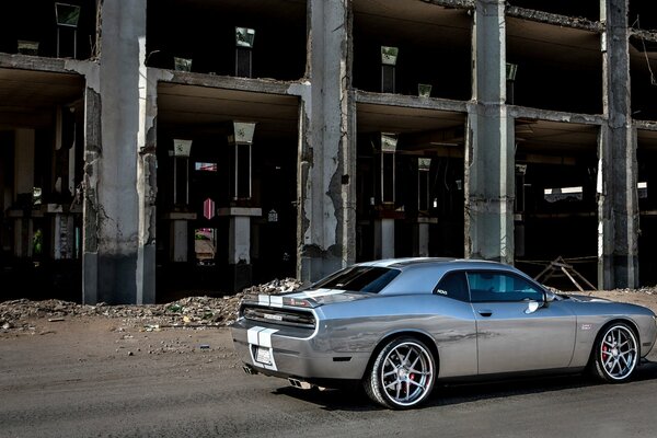 Coche gris chalenger en el fondo del edificio vista lateral