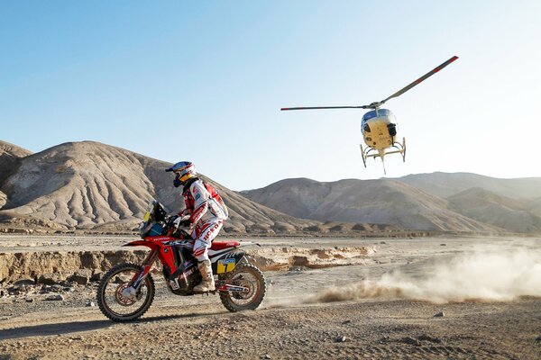 A racer participating in the Dakar race and a helicopter