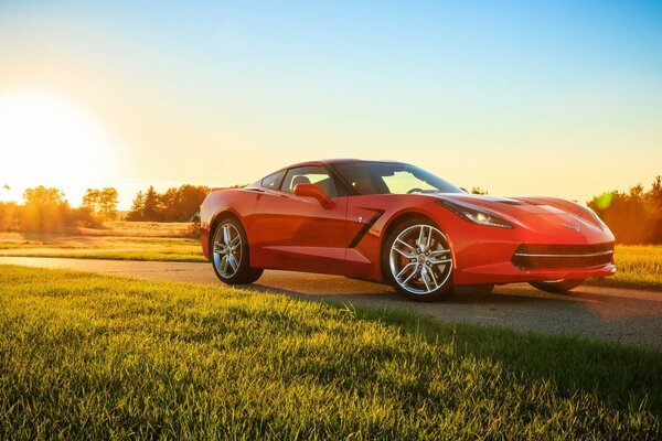 Вид сбоку на красный Chevrolet Corvette в лучах солнца