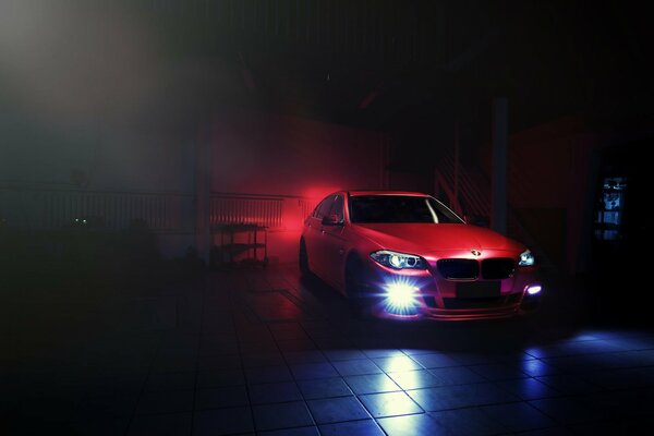 Red BMW F10 with headlights on in the dark