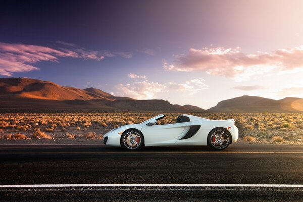 White car on the background of mountains at sunset