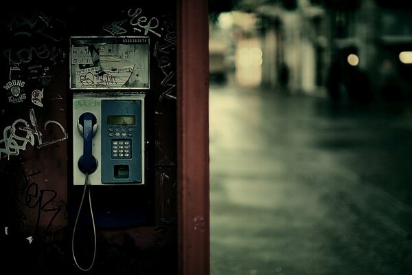 A telephone booth in the middle of a rainy city