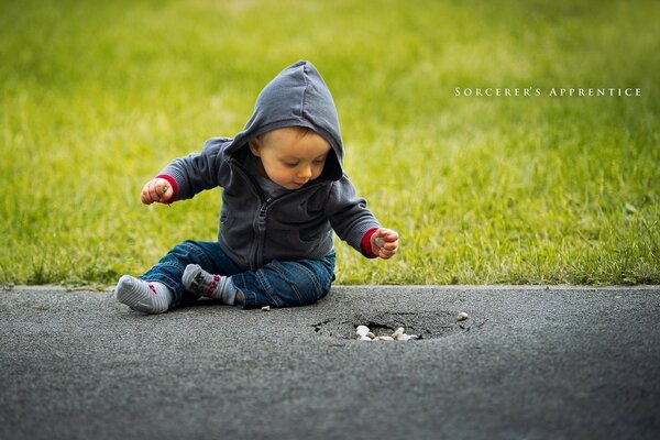 Niño pequeño sentado en el asfalto