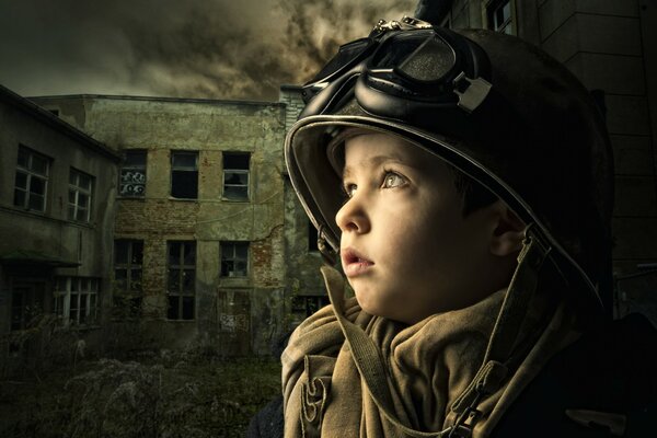 A little boy looks at the sky against the background of an abandoned building