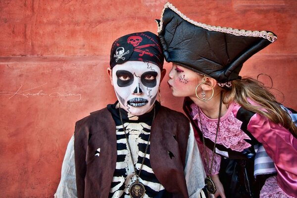 A girl in a pirate costume kisses a guy