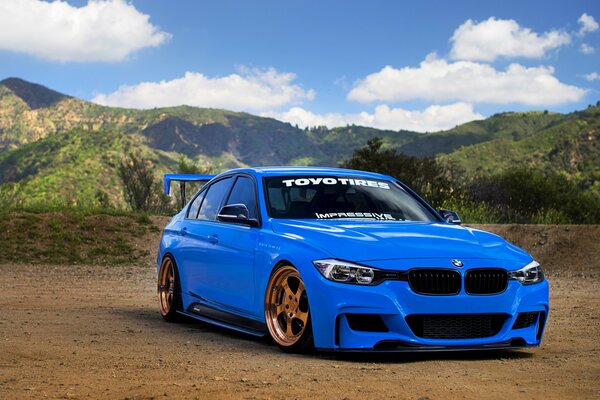 Voiture BMW série 3 en bleu sur fond de montagnes