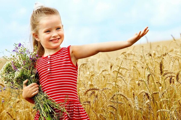 Bambino con un mazzo di fiori in un campo di grano