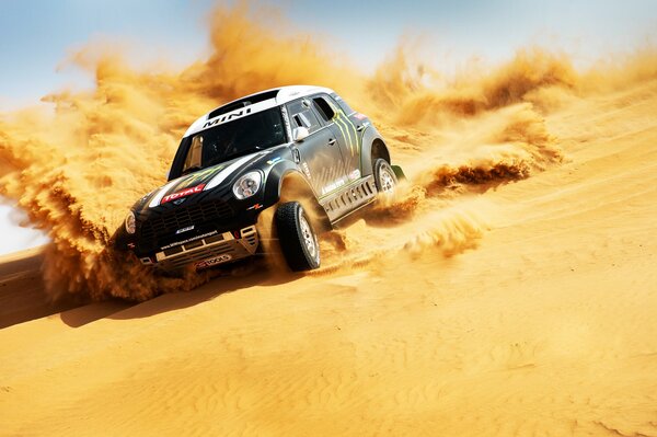 Une voiture de sport dans le désert roule sur le sable