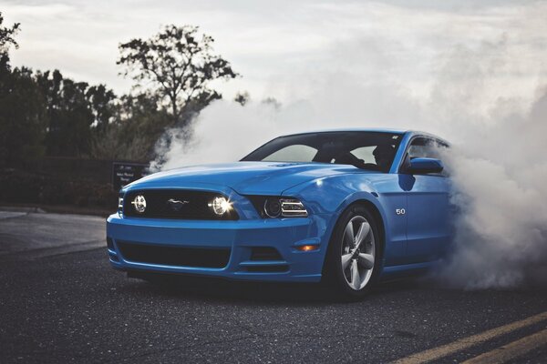 Blue Ford Mustang on the road in smoke