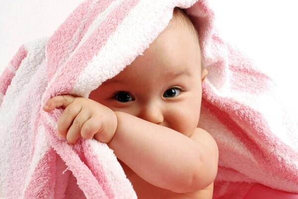 Un enfant se cache sous un couvre-lit rose