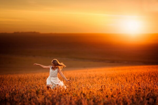 Chica en un campo de trigo en el fondo de la puesta de sol