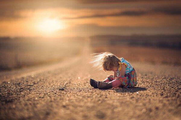 Samotne dziecko siedzi na drodze