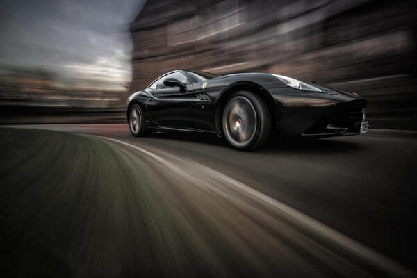 Czarne Ferrari California prędkość w ruchu z rozmytym tłem