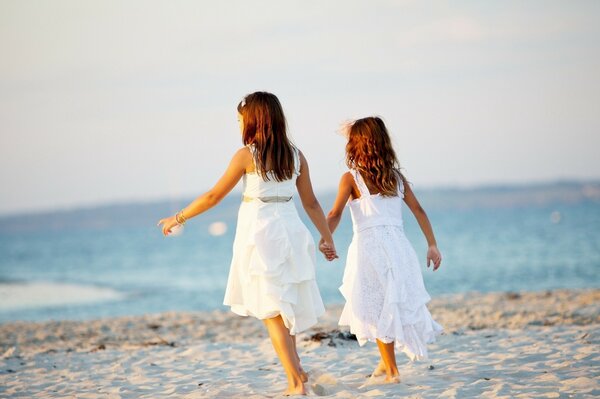 Due ragazze sulla spiaggia si tengono per mano