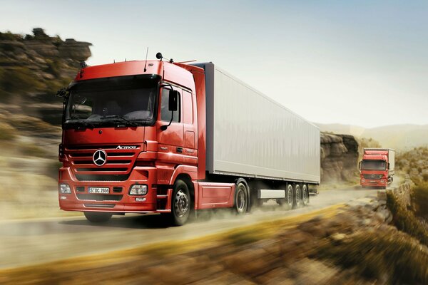 I camion con i trattori Mercedes corrono lungo la strada ad alta velocità
