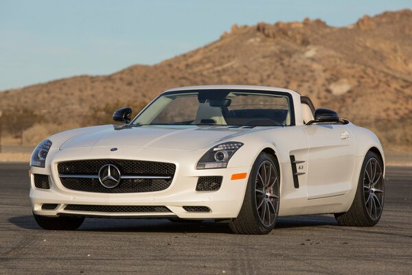 White Mercedes convertible with black wheels on the background of mountains