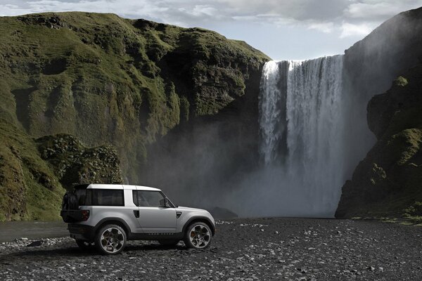 Coche land rover en el fondo de una hermosa cascada