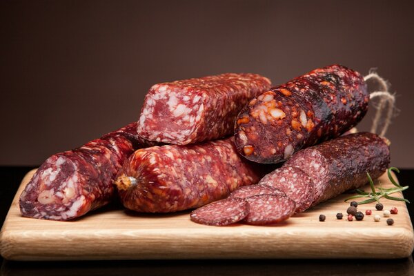 Slicing raw smoked sausage on a board