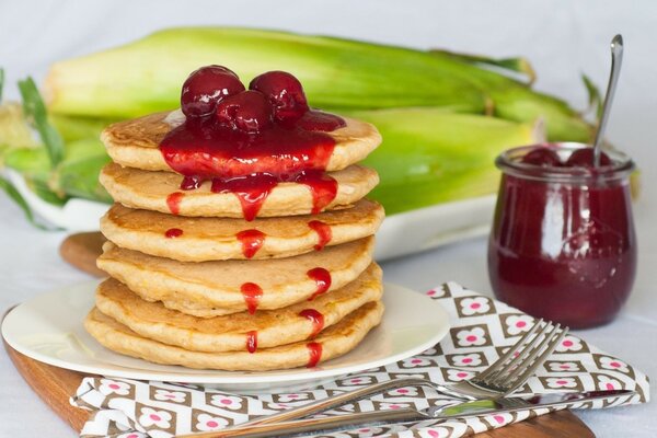 Pancakes doused with cherry jam on a plate