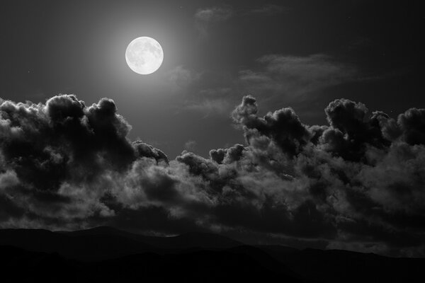 Pełnia księżyca na czarnym niebie z chmurami
