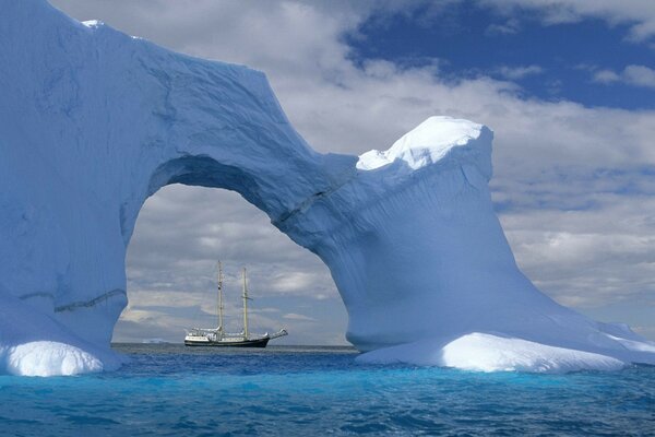 A sailboat in the sea and a beautiful iceberg