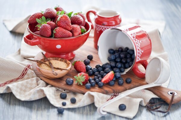 Tasse mit Erdbeeren, Blaubeeren auf einer Tafel