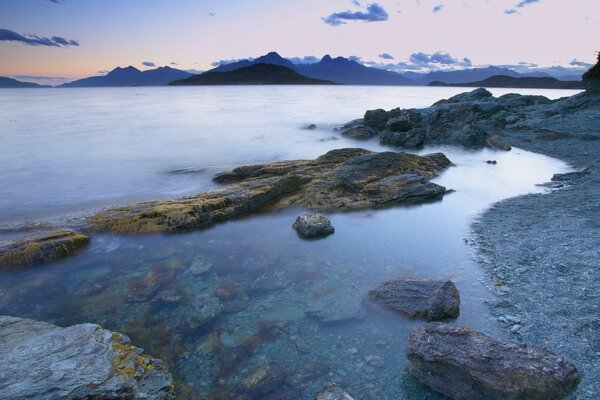 Rocks on the shore . Mountains. The clouds