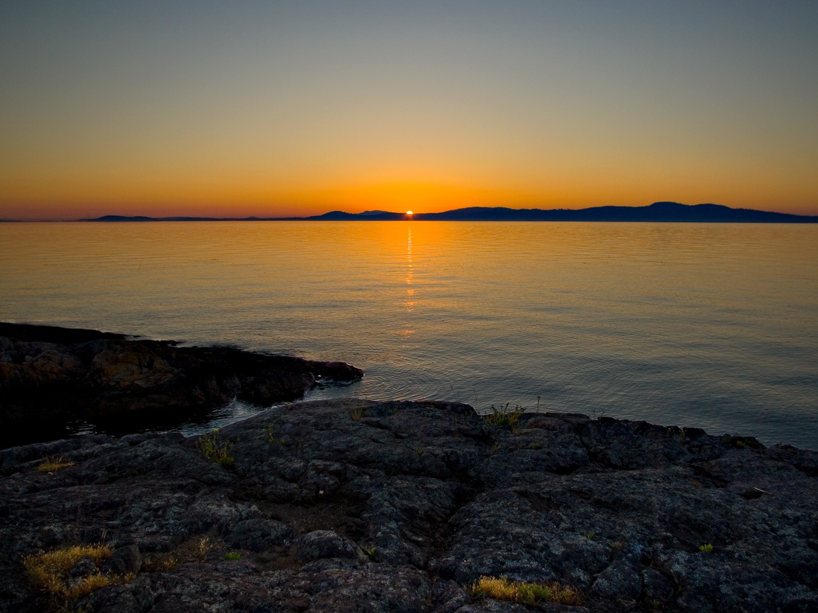 puesta de sol orilla piedras lago