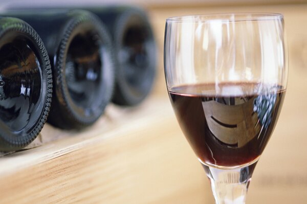 Red wine in a glass, bottles