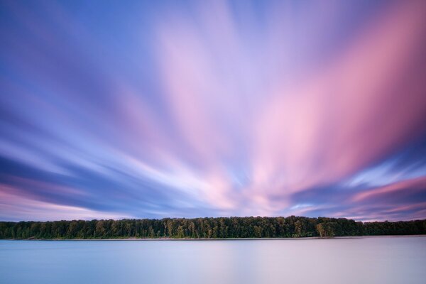 Pink clouds over the forest and lake