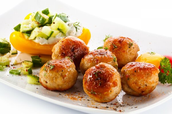 Boulettes de viande avec des légumes cuits sur une plaque blanche