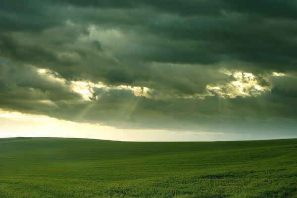 Blick auf das Feld und die Sonnenstrahlen durch die Wolken