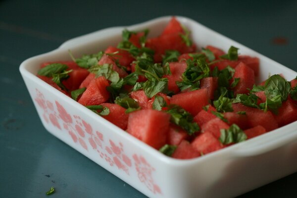 Sliced watermelon in a plate with herbs