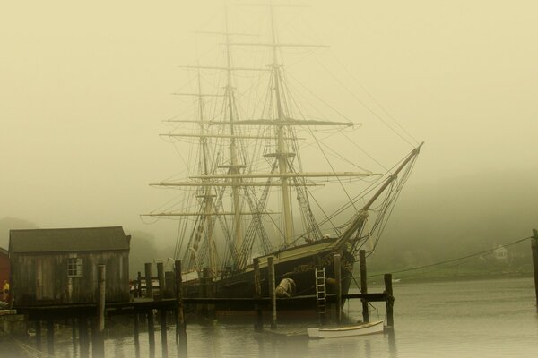 A lone sailboat is moored at the pier, which is surrounded by fog