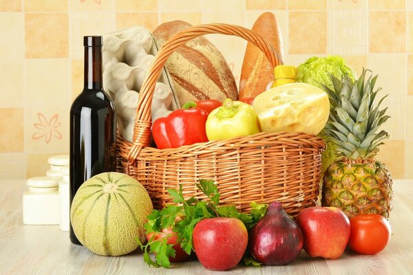 Basket with vegetables, bread, eggs and wine next to it