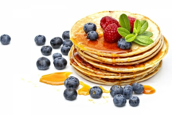 Pancakes with raspberries and blueberries, poured with honey