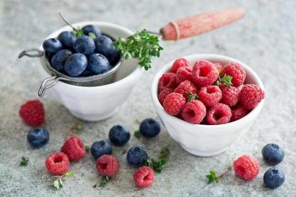 Raspberries and blueberries in white porcelain cups