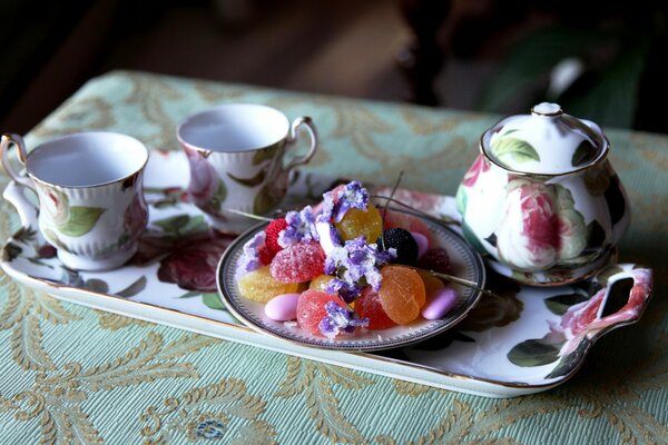 Porcelain tea set on a beautiful tray with sweets on a plate