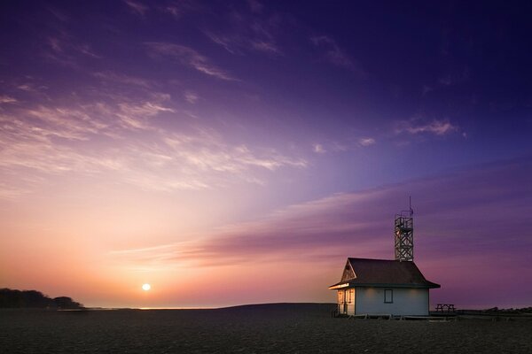 House on the seashore, against the background of the sky and the sun