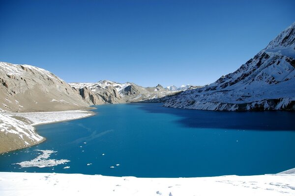 The mountain lake is covered with snow
