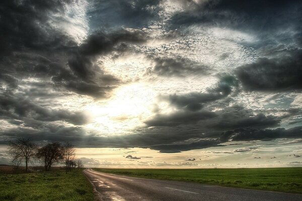 Route dans le champ. Soleil et nuages