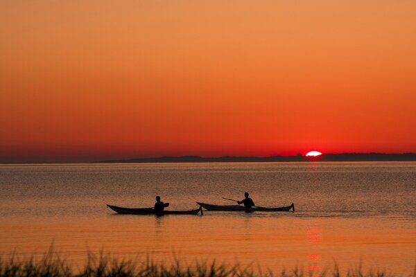 Landscape with a lake and two boats at sunset