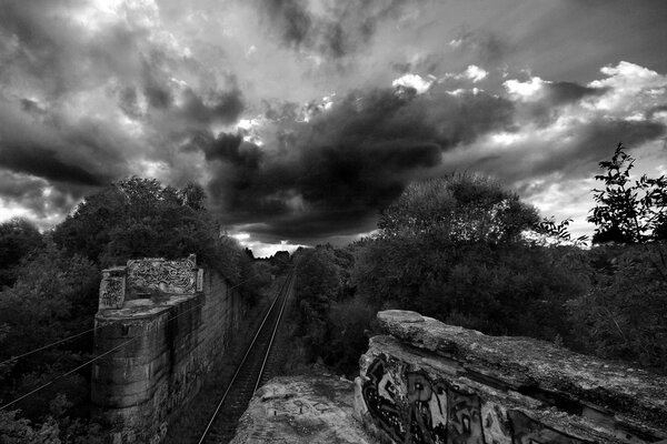 Schwarz-Weiß-Bild mit Graffiti-Eisenbahn und Gewitterwolken