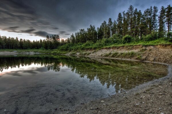 Bäume und Wolken spiegeln sich im Wasser wider