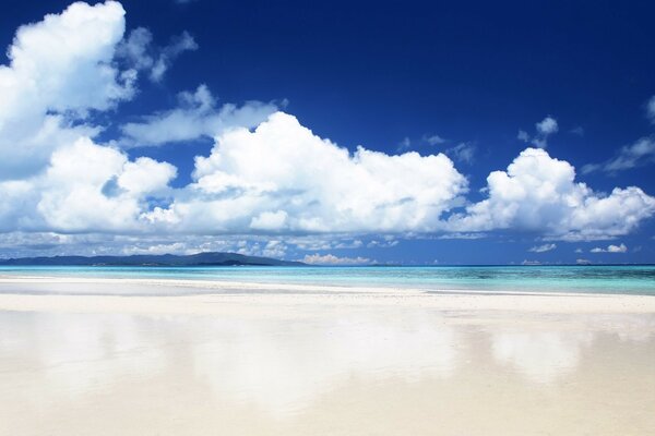 Große weiße Wolken und weißer Strand